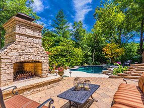 outdoor fireplace, patio and pool in a woodland garden